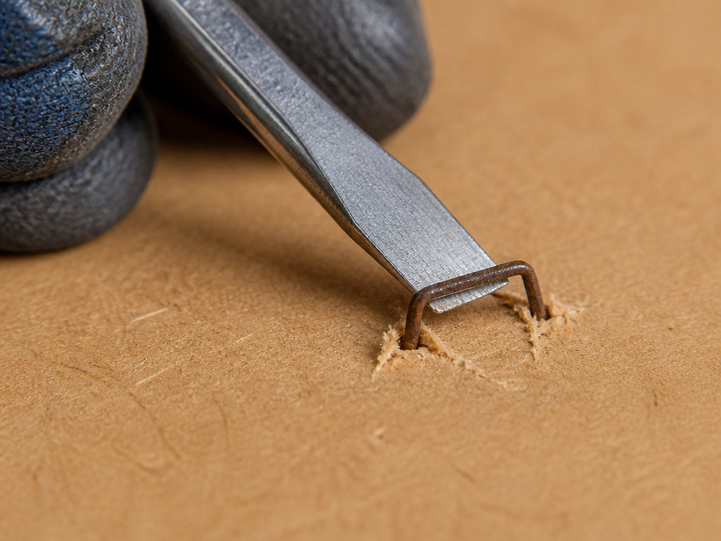 Removing a rusted staple from engineered MDF wood with a screwdriver.