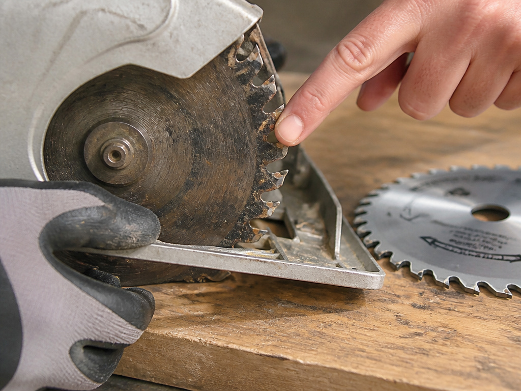 Close-up inspection of dirty circular saw blade causing crooked cuts.